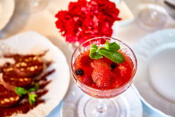 Strawberry dessert with mint is on a glass plate in the restaurant
