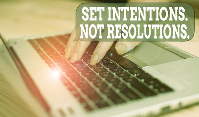 Writing note showing Set Intentions Not Resolutions. Business concept for Positive choices for new start achieve goals woman with laptop smartphone and office supplies technology