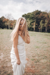 Naklejka premium Blonde happy girl laughs and runs on the grass. The girl in a white sundress laughs and enjoys life. Lifestyle in nature.