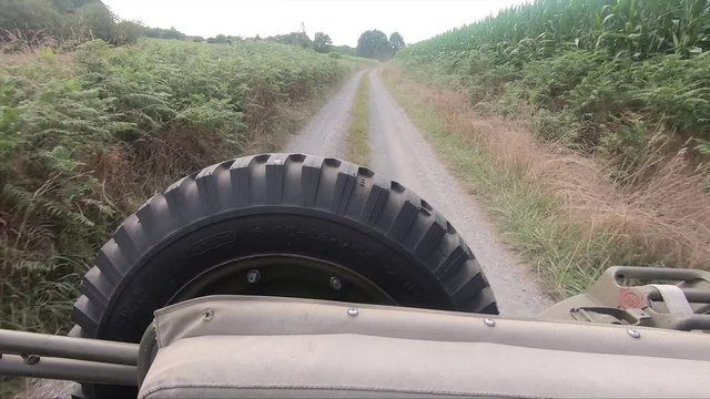 Military 4X4 car driving on small road, back view