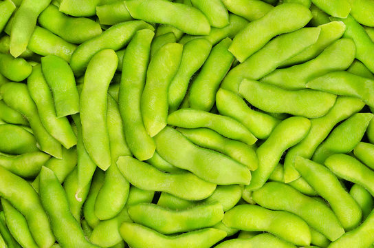 Edamame, green soybeans in the pod, background. Unripe soya beans, also Maodou. Glycine max, a legume, edible after cooking and a rich protein source. Closeup, macro food photo.