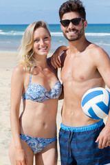 picture of a couple on the beach holding volleyball