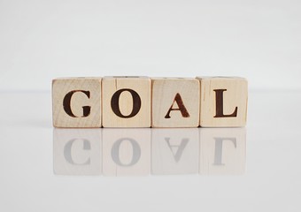 Word GOAL made with wooden cubes, isolated on white background with reflection.