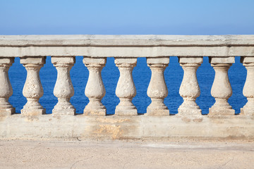Fototapeta na wymiar Old stone balustrade with blue sea and sky