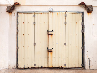 Old yellow metal gate in stone wall, front view