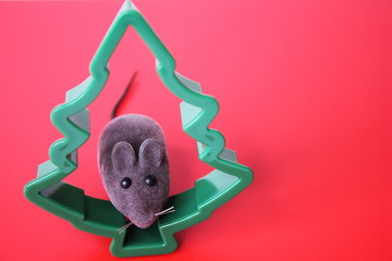 Mouse is a Symbol of new year 2020. Toy mouse and the figure of a Christmas tree on a red background