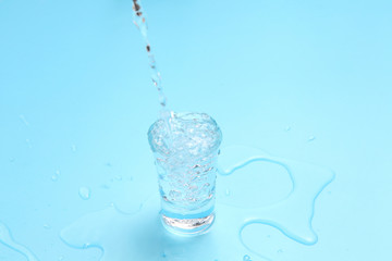 pouring vodka to shot glass on blue background with a blank space for a text, Russian vodka on color table