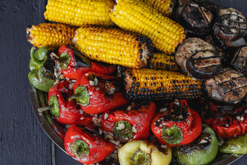 Grilled vegetables on plate on wooden background. Pepper, corn and eggplant cooked on grill. BBQ. Barbecue. Organic salad