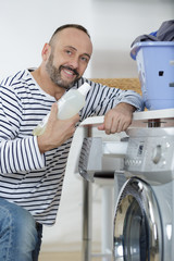 Obraz premium man loading clothes into washing machine in kitchen