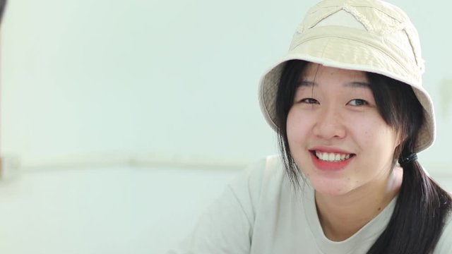 Smiling Beautiful Asian student girl daydreaming in high school classroom or reading book alone in class at front whiteboard at looking happiness in study, Education learning by myself