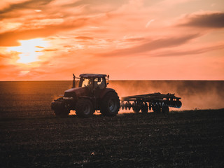 Tractor on filed by sunset.