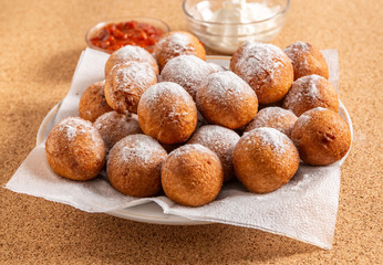 Round doughnuts, sprinkled with powdered sugar, lie on a plate