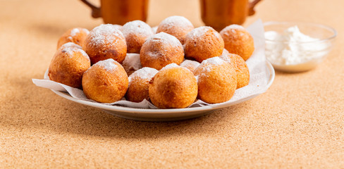 Round doughnuts, sprinkled with powdered sugar, lie on a plate