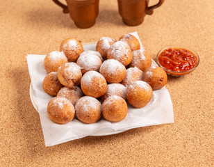 Round doughnuts, sprinkled with powdered sugar, lie on a plate
