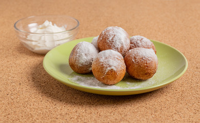 Round doughnuts, sprinkled with powdered sugar, lie on a plate