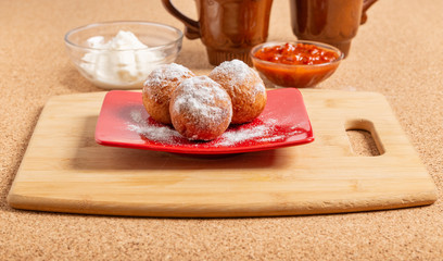 Round doughnuts, sprinkled with powdered sugar, lie on a plate