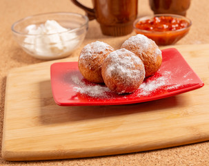 Round doughnuts, sprinkled with powdered sugar, lie on a plate