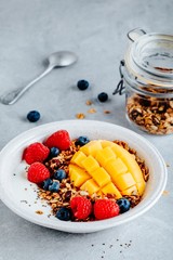 Healthy breakfast bowl homemade granola with fresh blueberry, raspberry and mango