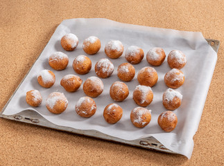 Donuts sprinkled with powdered sugar lie on a baking sheet. Textures.