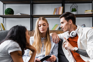 selective focus of handsome and attractive multicultural friends talking in apartment