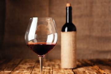 Red wine in a wine glass on the background of a wine bottle.