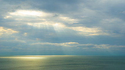 Fototapeta na wymiar emerald sea scape under a dense clouds with pushing sunrays