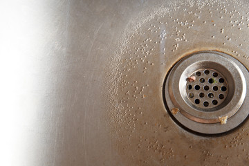 Dirty sink drain with leftover food. Stainless steel sink.