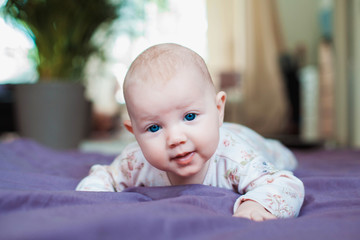 Casual portrait of three months old baby lying on tummy in bed at home.