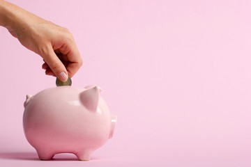 woman hand putting money coin into piggy for saving money wealth and financial concept.