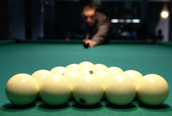 Billiard balls at the beginning of the game, in the background a blurred figure of the player.