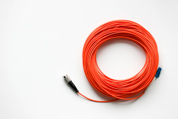 Orange optical fiber network cable with blue and black connectors isolated on white background