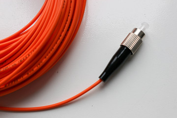 Orange optical fiber network cable with black connector isolated on white background close up
