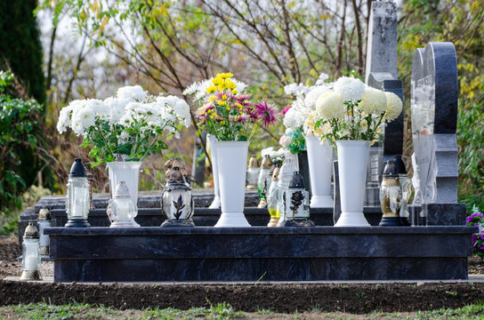 Marble tombstone in a European cemetery - full of flowers and lamps with candle - all souls day decoration and remembrance 