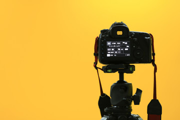 A back black camera on tripod shooting to yellow screen.
