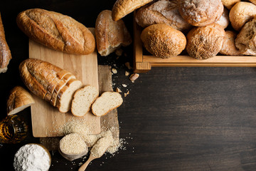Fresh loaves of bread And sliced ​​breads containing sesame seeds, honey placed on a black wooden table. Top view
