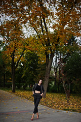 Fototapeta premium A tall leggy young beautiful and elegant model woman at formal wear posed at autumn background.