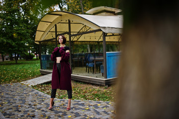 A tall leggy young beautiful and elegant model woman at claret coat.