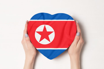 Flag of North Korea on a heart shaped box in a female hands. White background