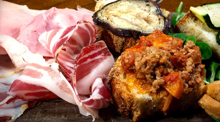 Food: typical Italian salami, cheese and vegetable platter: ham, salami, aubergine, courgette, bread, meat and tomato. Rustic catering.