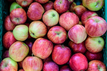 Fresh ripe red apples from orchard, displayed for sale in a plastic box, at a street food market, soft focus