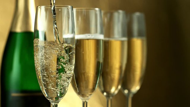 Super slow motion of pouring Champagne wine into glasses, closeup view. Filmed on high speed cinema camera, 1000fps