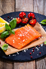 Fresh raw salmon fillets on black stone plate