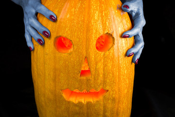 Hands of a dead woman on a Jack-o'-lantern. Isolated on white background.