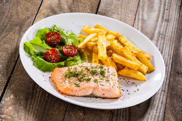 Fried salmon with french fries on wooden table