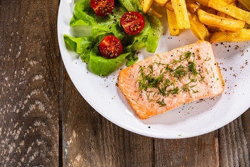 Fried salmon with french fries on wooden table