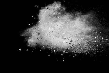 Split debris of stone exploding with white powder against black background.