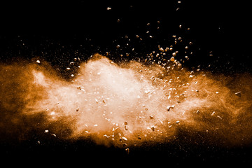 Fototapeta na wymiar Split debris of stone exploding with orange powder against black background.