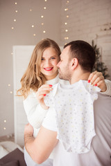 Beautiful pregnant woman and her handsome husband are holding baby bodysuit and smiling
