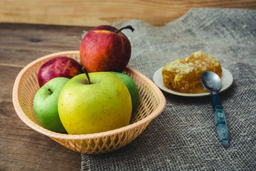 Honeycombs with honey and slices of ripe apples on wooden table.