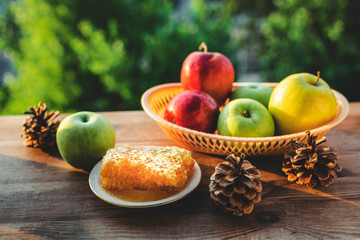 Honeycombs with honey and slices of ripe apples on plate in the garden.